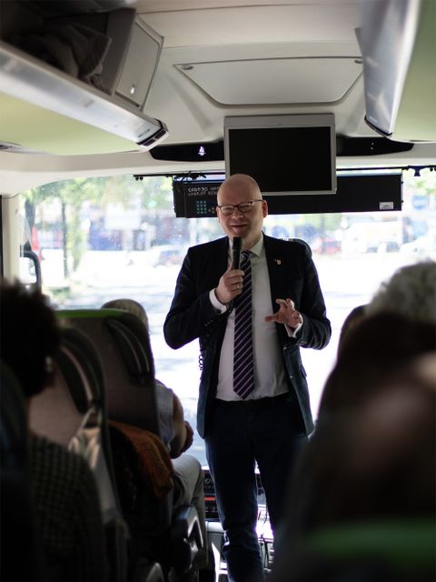Bildvergrößerung: Bezirksstadtrat Tim Richter begrüßt die Teilnehmenden der Tagesfahrt im Bus