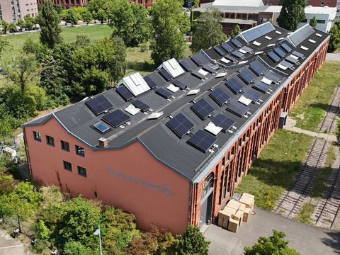 Gewinner 1. Platz Architekturwettbewerb. Eine Halle mit Solaranlage auf dem Dach, aus der Luft fotografiert.