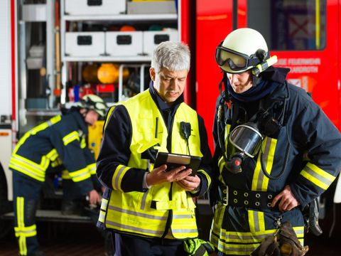 Zwei Feuerwehrmänner planen am Tablet-Computer einen Einsatz