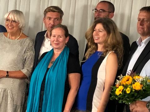 4. September 2024: Kulturstaatssekretärin Claudia Roth (1.v.l.) auf der Bühne u.a. mit Dr. Christine Glauning (mit blauem Schal), Leiterin des Dokumentationszentrums NS-Zwangsarbeit, Panagiota Constantinopoulou (2.v.r.), Gesandte der griechischen Botschaft, sowie Oliver Friederici (1.v.r.), Staatssekretär für Gesellschaftlichen Zusammenhalt im Land Berlin