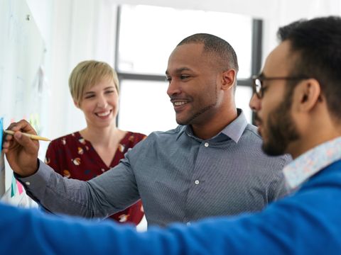 Drei Menschen stehen an einem Flipchart