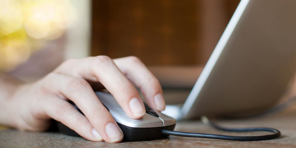 Hand auf der Maus neben einem Laptop