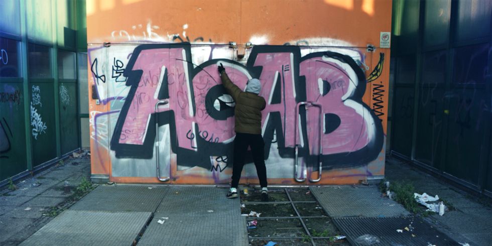Sprayer an der Wand mit Graffiti Acab