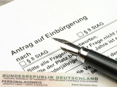 Antrag auf Einbürgerung in Deutschland, darauf liegt ein Deutscher Personalausweis und ein Füllfederhalter