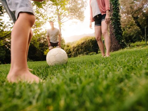 Family playing football in garden lawn