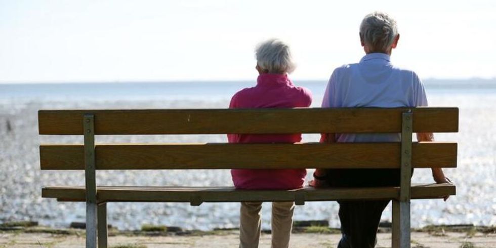 Älteres Paar auf einer Bank am Strand