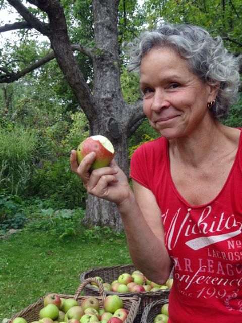 Katja Gurkasch, mit angebissenem Apfel, schaut verschmitzt in die Kamera