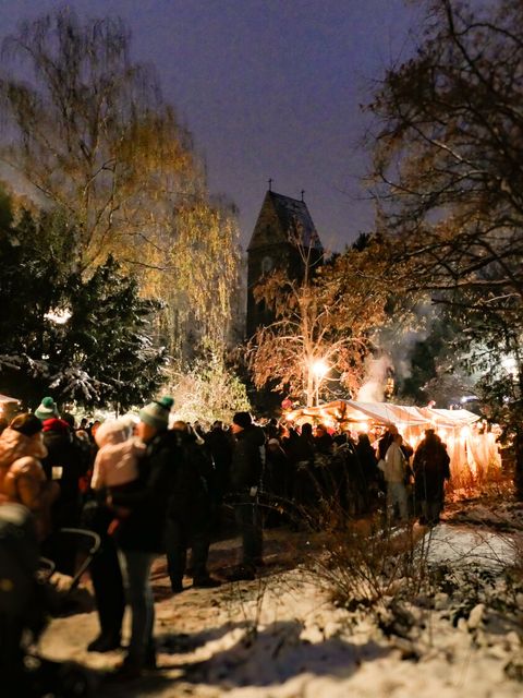 Bildvergrößerung: Menschen auf einem Weihnachtsmarkt im Licht von Lichterketten