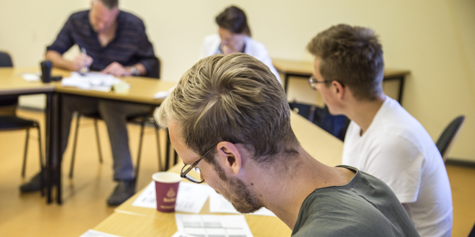 Umfrage - mehrere Teilnehmende sitzen an einem Tisch und füllen etwas aus