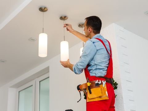 Electrician man worker installing ceiling lamp