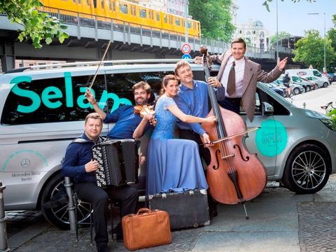 Mitwirkende der Komischen Oper vor einem Kleinbus in Berlin