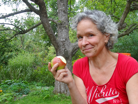 Katja Gurkasch mit angebissenem Apfel im Garten