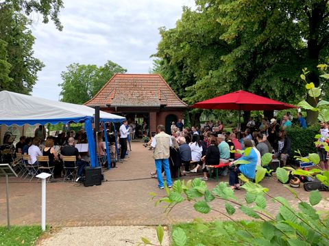 Bildvergrößerung: Promenadenkonzert Landhausgarten - Menschen sitzen unter Pavillon im Landhausgarten
