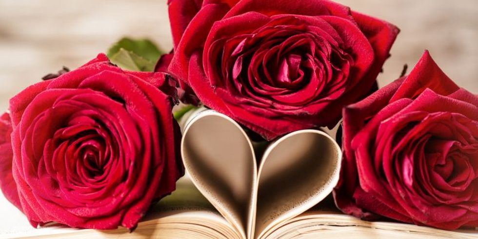 Ein aufgeschlagens Buch, dessen innere Seiten ein von drei roten Rosen umrahmtes Herz bilden.