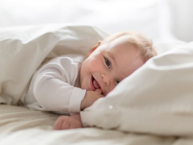 Cute happy 7 month baby girl in diaper lying and playing