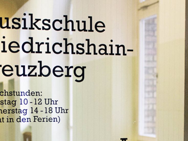 Glastür mit Schriftzug "Musikschule Friedrichshain-Kreuzberg" und Sprechstunden