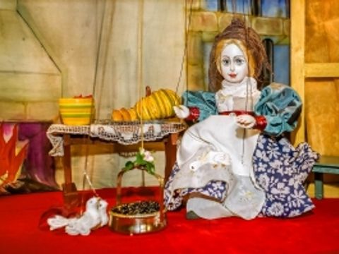 Puppentheater-Szene: Mädchen in einer Küche mit zwei Tauben und eine Schale mit Körnern