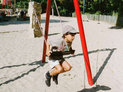 Ein Kind schaukelt auf einem Spielplatz in Neukölln. Das Bild zeigt eine saubere, einladende Umgebung und symbolisiert die familienfreundliche Atmosphäre im Kiez.