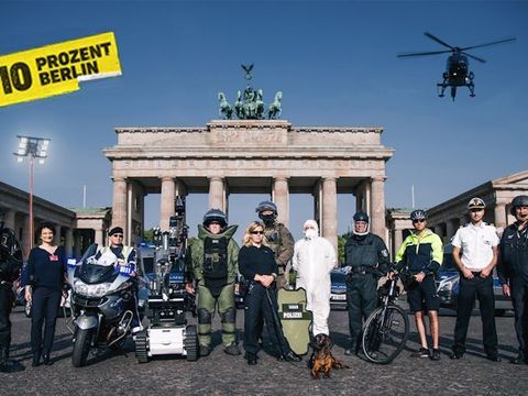 Polizisten in ihren Arbeitsbereichen vor dem Brandenburger Tor, Links oben Logo Kampagne 110 Prozent Berlin