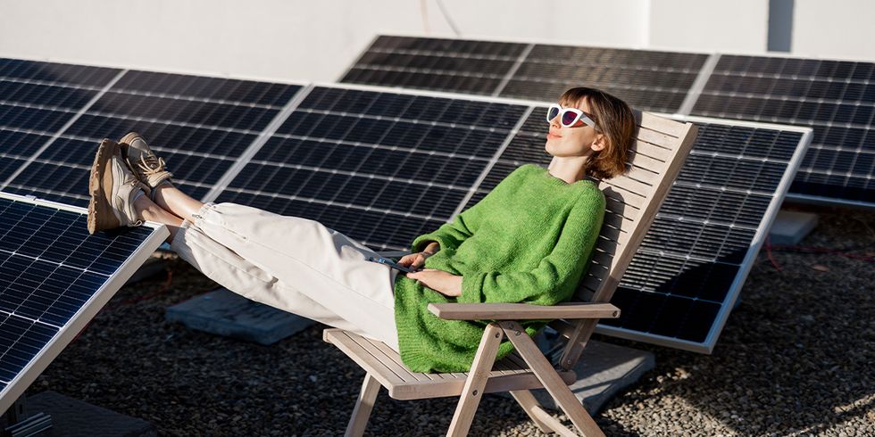 Frau mit Sonnenbrille auf Liegestuhl zwischen Solarpanelen
