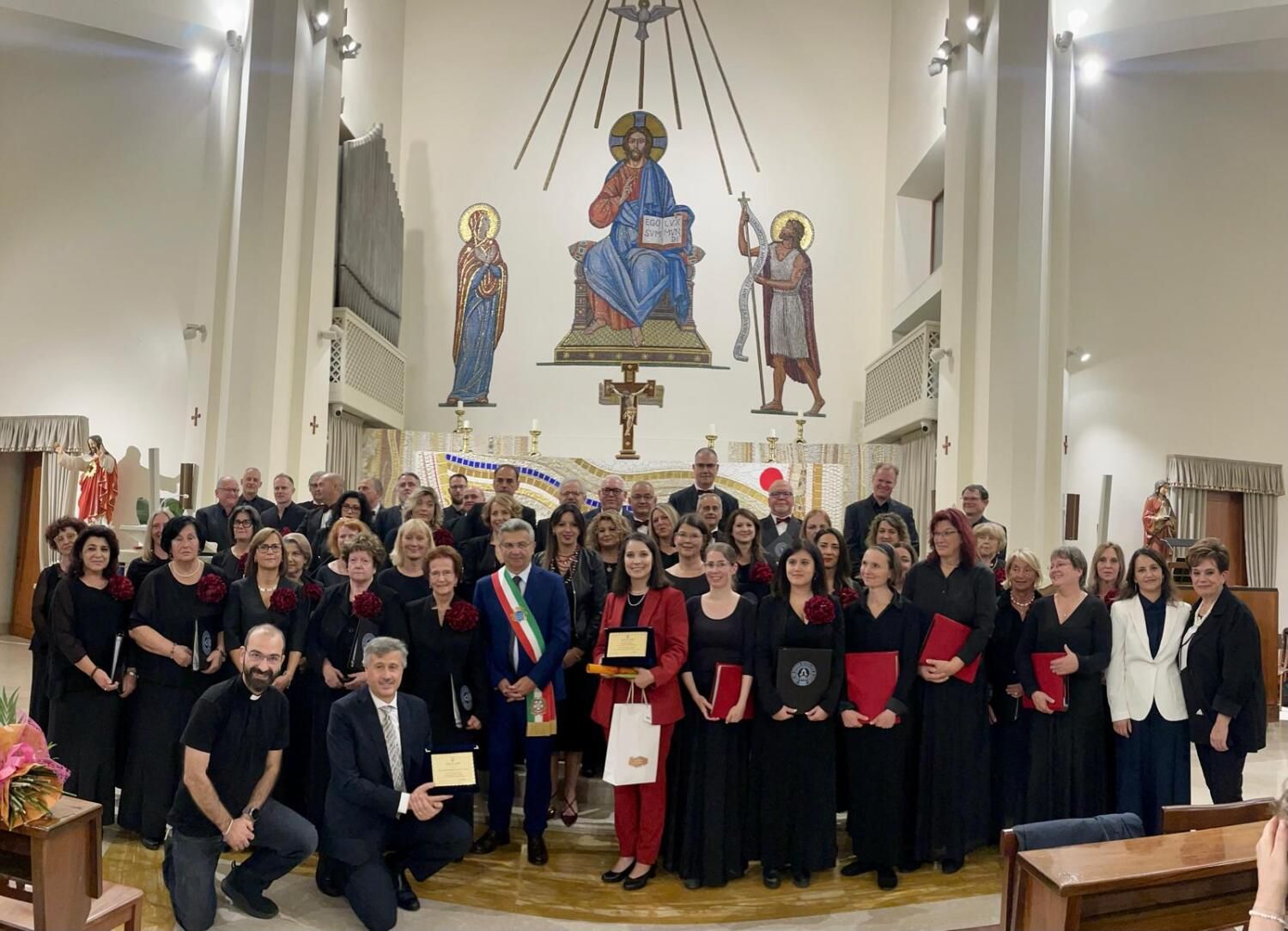 5. Oktober 2024: Vollversammlung zweier Chöre beim Jubiläumskonzert in San Giovanni Battista, Cassino (mit Schärpe: Bürgermeister Enzo Salera, rechts daneben Chorleiterin Claudia Jennings; knieend vorne links der Gemeindepfarrer, rechts daneben Chorleiter Fulvio Venditti)