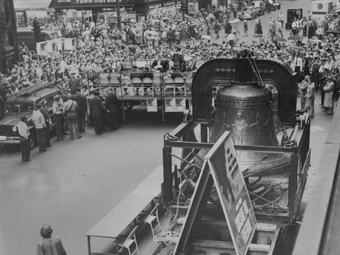 Enlarge photo: A large bell on a trailer is surrounded by a big crowd.