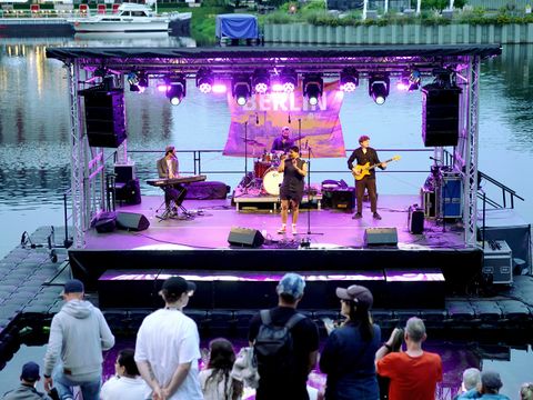 schwimmende Bühne im lila Licht mit einer Band