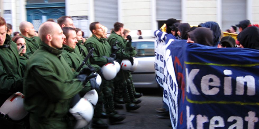 buehne_Eine Gruppe von Polizisten kämpfen auf einer Straße gegen eine Gruppe Demonstranten an