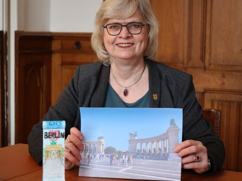 Zeigt ein Bild des Budapester Heldenplatzes: Bezirksschulstadträtin Cerstin Richter-Kotowski; daneben ein Exemplar eines von Schülern bemalten Miniatur-Mauersegments