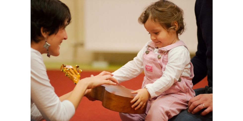 Musikalische Frühförderung: Hören, Erfahren, Begreifen und Fühlen. Kleinkind fässt ein Instrument an. 