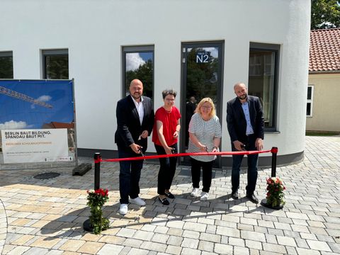 Bildvergrößerung: Bezirksbürgermeister Frank Bewig, Schul- und Sportamtsleiterin Astrid Knüppel, Schulstadträtin Dr. Carola Brückner und Malek Saleh, stellv. Schulleiter der Schule am Staakener Kleeblatt, beim feierlichen Banddurchschnitt vor dem neuen Werkstattgebäude. 