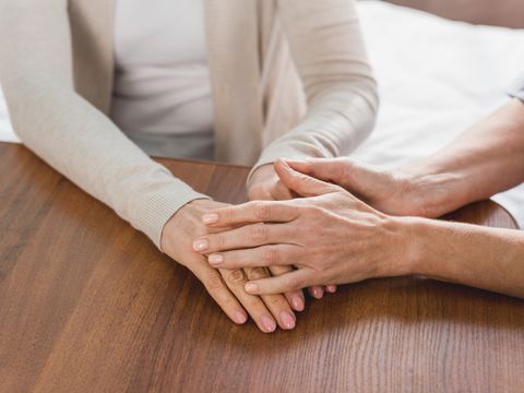 Close-up partial view of nurse and senior patient holding hands