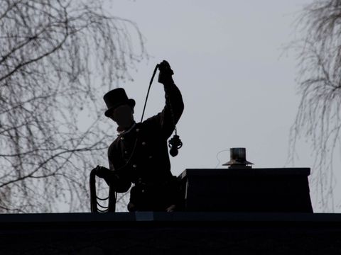 Ein Schattenbild mit einem Schornsteinfeger auf dem Dach