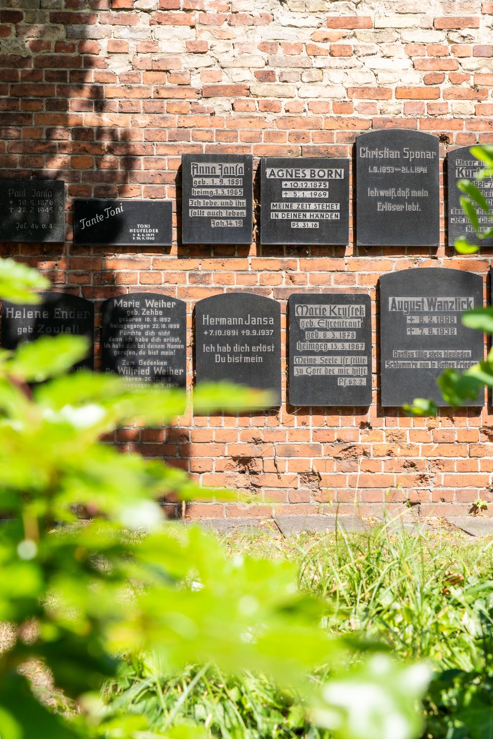 Friedhofsmauer mit schwarzen Grabplatten