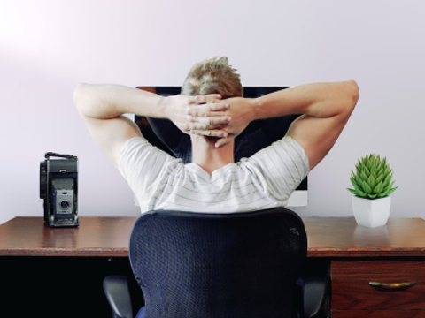 Ein Mann sitzt vor seinem Monitor am Schreibtisch und schlägt die Hände über dem Kopf zusammen.