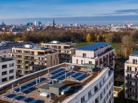 Stadtsilhouette am Horizont, Im Vordergrund moderne Flachdächer mit Solaranlagen