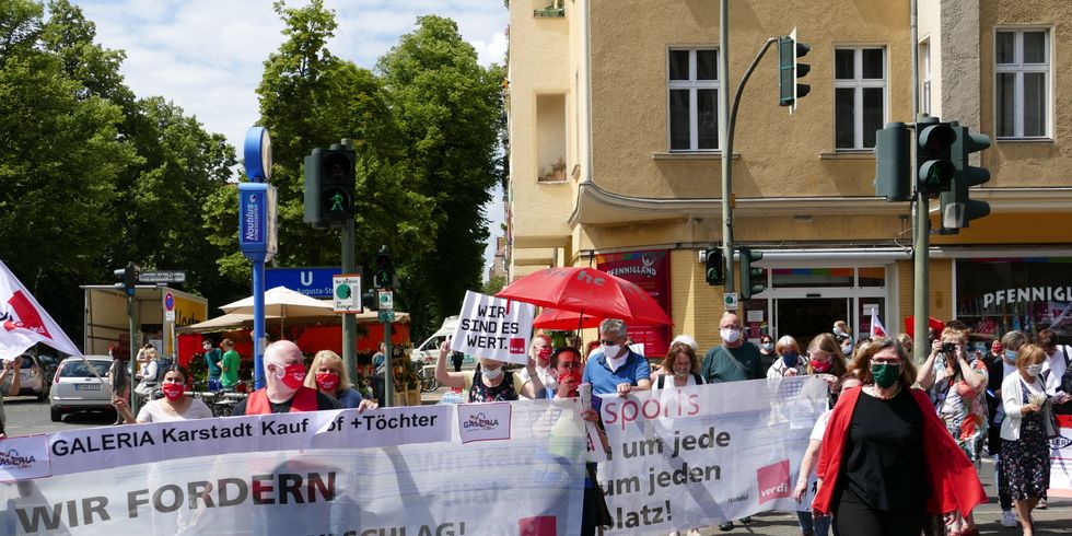 Mehrere Menschen laufen mit Transparenten auf einer Straße lang.