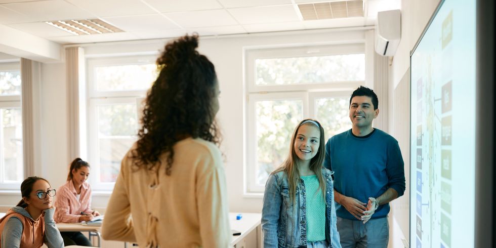 Schülerinnen und Lehrer stehen vor einem Smartboard