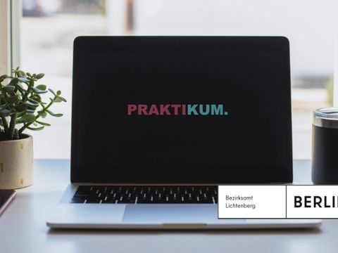 Laptop mit Schriftzug Praktikum, Tasse, Pflanze, Smartphone auf dem Schreibtisch