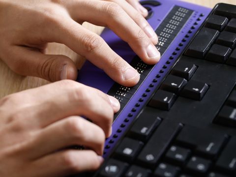 Blind person using computer with braille computer display 