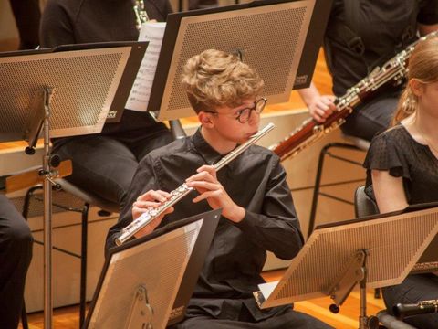 Junge spielt Querflöte im Orchester