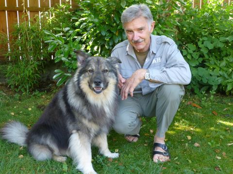 Josef Reichholf hockt mit seinem Hund auf einer Wiese