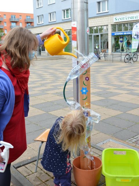 Eine Frau gießt mit Kind Wasser in eine Plastikflasche