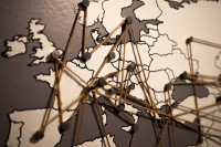Auf dem Bild ist eine Karte von Europa dargestellt. Ein Faden verbindet über Stecknadeln Orte aus verschiedenen Ländern.