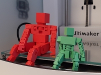 zwei kleine Roboter aus dem 3D-Drucker sitzen auf selbigen