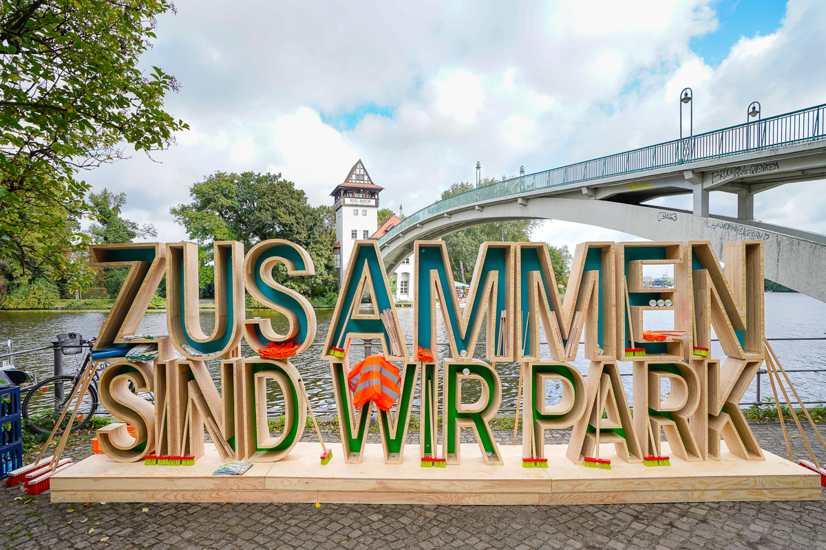 Schriftzug "Zusammen sind wir Park" mit Aufräumequipment