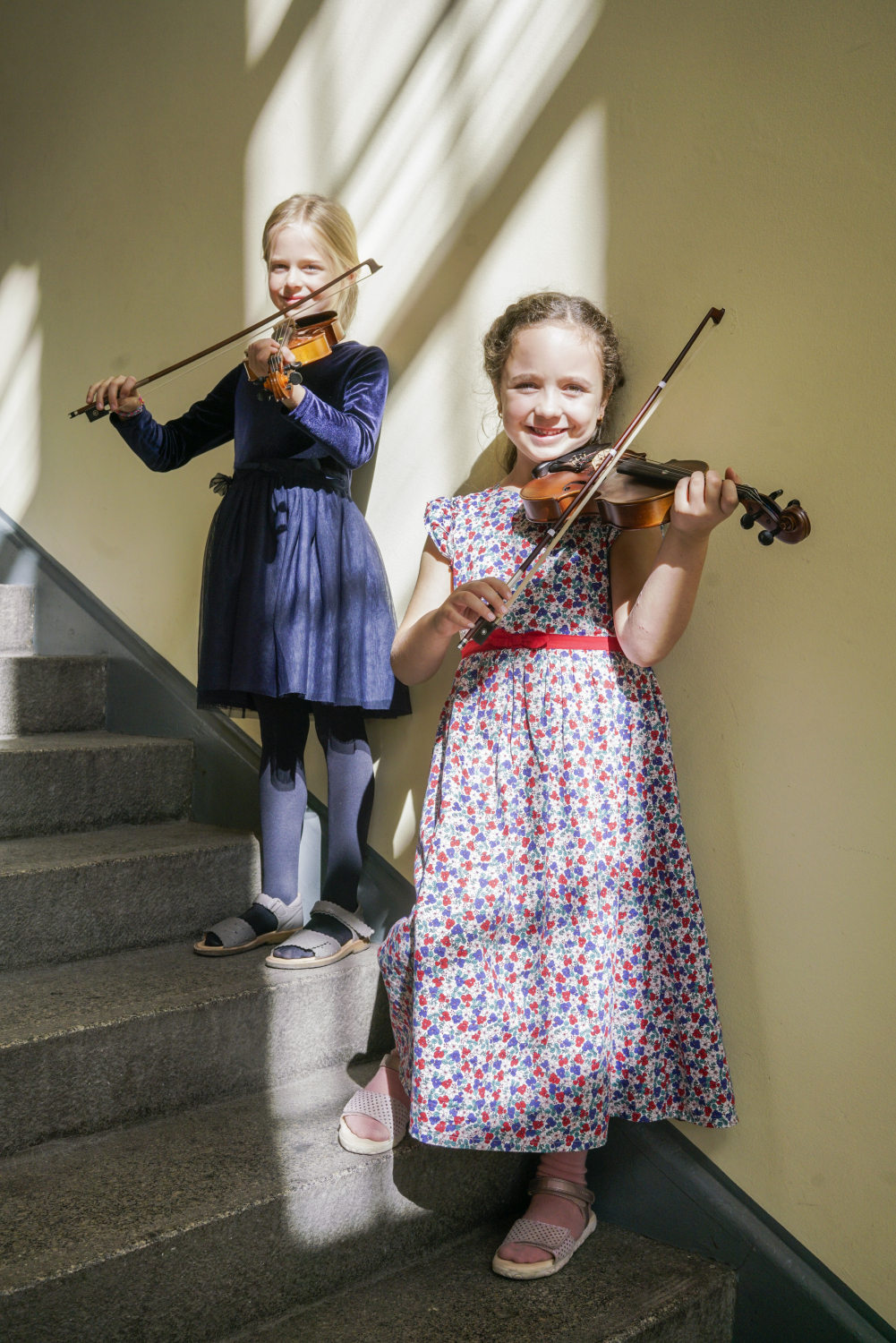 Zwei glückliche Mädchen spielen zusammen Geige.