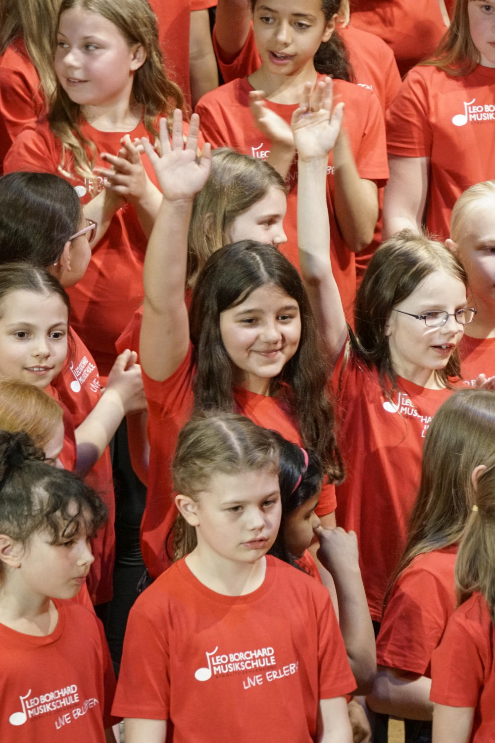 Kinder in roten T-shirts, ein Mädchen reißt die Arme hoch