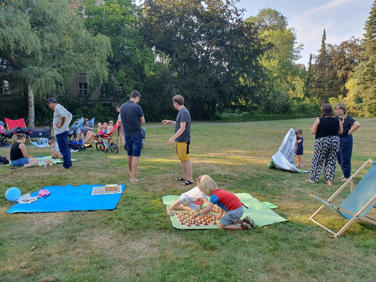 Familien mit Kindern sitzen auf Picknickdecken in einem Park