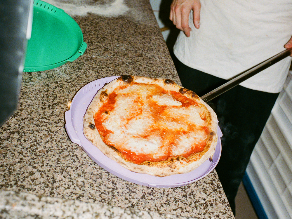 Eine frisch gebackene Pizza wird in einer Mehrweg-Verpackung serviert. Das Bild zeigt, wie Mehrweg-Konzepte in der Gastronomie umsetzbar sind und Abfall reduzieren.